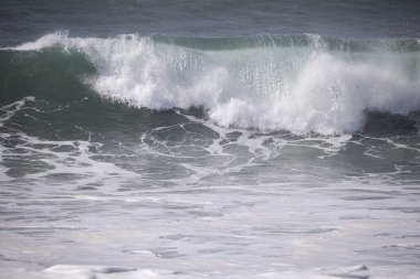 Büyük bir Atlantik dalgası Tazacorte sahiline çarpıyor. Beyaz köpük ve spreyle kırılan turkuaz suyun yakın çekimi denizin evcilleştirilmemiş gücünü gösteriyor. La Palma, Kanarya Adaları, İspanya