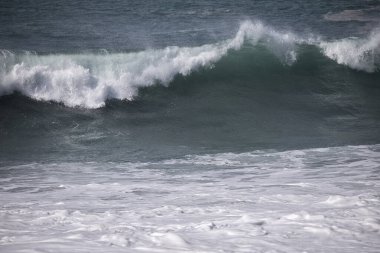 Büyük bir Atlantik dalgası Tazacorte sahiline çarpıyor. Beyaz köpük ve spreyle kırılan turkuaz suyun yakın çekimi denizin evcilleştirilmemiş gücünü gösteriyor. La Palma, Kanarya Adaları, İspanya