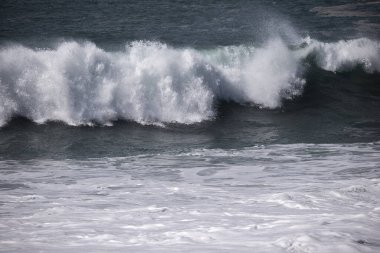 Büyük bir Atlantik dalgası Tazacorte sahiline çarpıyor. Beyaz köpük ve spreyle kırılan turkuaz suyun yakın çekimi denizin evcilleştirilmemiş gücünü gösteriyor. La Palma, Kanarya Adaları, İspanya