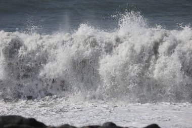 Büyük bir Atlantik dalgası Tazacorte sahiline çarpıyor. Beyaz köpük ve spreyle kırılan turkuaz suyun yakın çekimi denizin evcilleştirilmemiş gücünü gösteriyor. La Palma, Kanarya Adaları, İspanya