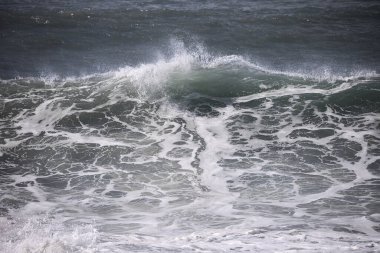 Büyük bir Atlantik dalgası Tazacorte sahiline çarpıyor. Beyaz köpük ve spreyle kırılan turkuaz suyun yakın çekimi denizin evcilleştirilmemiş gücünü gösteriyor. La Palma, Kanarya Adaları, İspanya