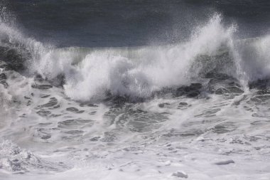 Büyük bir Atlantik dalgası Tazacorte sahiline çarpıyor. Beyaz köpük ve spreyle kırılan turkuaz suyun yakın çekimi denizin evcilleştirilmemiş gücünü gösteriyor. La Palma, Kanarya Adaları, İspanya