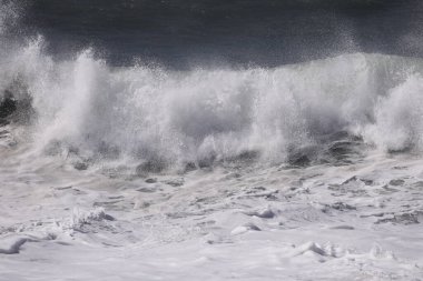 Büyük bir Atlantik dalgası Tazacorte sahiline çarpıyor. Beyaz köpük ve spreyle kırılan turkuaz suyun yakın çekimi denizin evcilleştirilmemiş gücünü gösteriyor. La Palma, Kanarya Adaları, İspanya