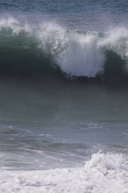 Büyük bir Atlantik dalgası Tazacorte sahiline çarpıyor. Beyaz köpük ve spreyle kırılan turkuaz suyun yakın çekimi denizin evcilleştirilmemiş gücünü gösteriyor. La Palma, Kanarya Adaları, İspanya