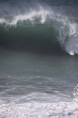 Büyük bir Atlantik dalgası Tazacorte sahiline çarpıyor. Beyaz köpük ve spreyle kırılan turkuaz suyun yakın çekimi denizin evcilleştirilmemiş gücünü gösteriyor. La Palma, Kanarya Adaları, İspanya