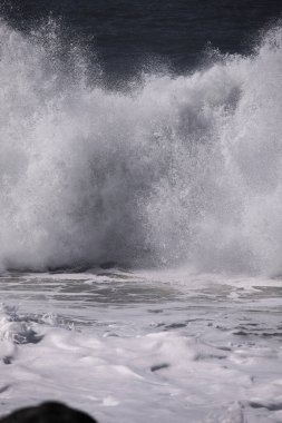 Büyük bir Atlantik dalgası Tazacorte sahiline çarpıyor. Beyaz köpük ve spreyle kırılan turkuaz suyun yakın çekimi denizin evcilleştirilmemiş gücünü gösteriyor. La Palma, Kanarya Adaları, İspanya