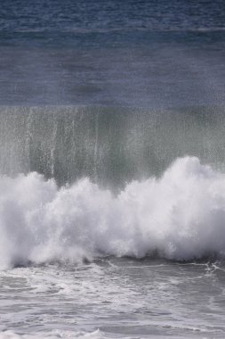 Büyük bir Atlantik dalgası Tazacorte sahiline çarpıyor. Beyaz köpük ve spreyle kırılan turkuaz suyun yakın çekimi denizin evcilleştirilmemiş gücünü gösteriyor. La Palma, Kanarya Adaları, İspanya