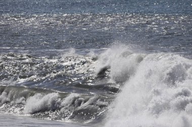 Büyük bir Atlantik dalgası Tazacorte sahiline çarpıyor. Beyaz köpük ve spreyle kırılan turkuaz suyun yakın çekimi denizin evcilleştirilmemiş gücünü gösteriyor. La Palma, Kanarya Adaları, İspanya