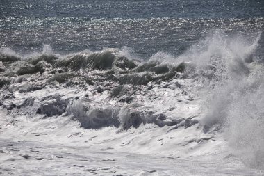 Büyük bir Atlantik dalgası Tazacorte sahiline çarpıyor. Beyaz köpük ve spreyle kırılan turkuaz suyun yakın çekimi denizin evcilleştirilmemiş gücünü gösteriyor. La Palma, Kanarya Adaları, İspanya