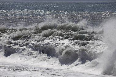 Büyük bir Atlantik dalgası Tazacorte sahiline çarpıyor. Beyaz köpük ve spreyle kırılan turkuaz suyun yakın çekimi denizin evcilleştirilmemiş gücünü gösteriyor. La Palma, Kanarya Adaları, İspanya