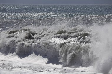 Büyük bir Atlantik dalgası Tazacorte sahiline çarpıyor. Beyaz köpük ve spreyle kırılan turkuaz suyun yakın çekimi denizin evcilleştirilmemiş gücünü gösteriyor. La Palma, Kanarya Adaları, İspanya