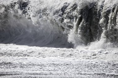 Büyük bir Atlantik dalgası Tazacorte sahiline çarpıyor. Beyaz köpük ve spreyle kırılan turkuaz suyun yakın çekimi denizin evcilleştirilmemiş gücünü gösteriyor. La Palma, Kanarya Adaları, İspanya