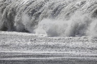 Büyük bir Atlantik dalgası Tazacorte sahiline çarpıyor. Beyaz köpük ve spreyle kırılan turkuaz suyun yakın çekimi denizin evcilleştirilmemiş gücünü gösteriyor. La Palma, Kanarya Adaları, İspanya