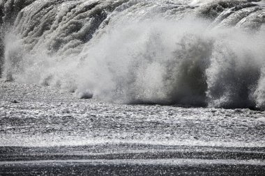 Büyük bir Atlantik dalgası Tazacorte sahiline çarpıyor. Beyaz köpük ve spreyle kırılan turkuaz suyun yakın çekimi denizin evcilleştirilmemiş gücünü gösteriyor. La Palma, Kanarya Adaları, İspanya