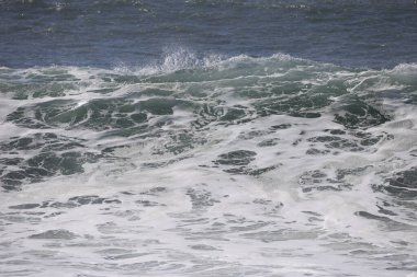 Büyük bir Atlantik dalgası Tazacorte sahiline çarpıyor. Beyaz köpük ve spreyle kırılan turkuaz suyun yakın çekimi denizin evcilleştirilmemiş gücünü gösteriyor. La Palma, Kanarya Adaları, İspanya