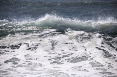 Büyük bir Atlantik dalgası Tazacorte sahiline çarpıyor. Beyaz köpük ve spreyle kırılan turkuaz suyun yakın çekimi denizin evcilleştirilmemiş gücünü gösteriyor. La Palma, Kanarya Adaları, İspanya