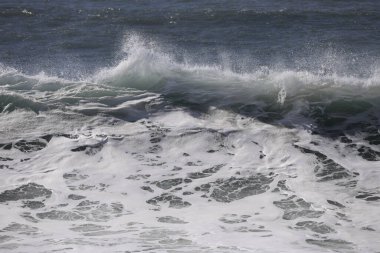 Büyük bir Atlantik dalgası Tazacorte sahiline çarpıyor. Beyaz köpük ve spreyle kırılan turkuaz suyun yakın çekimi denizin evcilleştirilmemiş gücünü gösteriyor. La Palma, Kanarya Adaları, İspanya