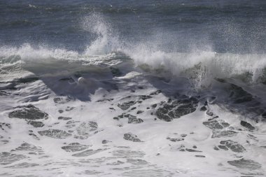 Büyük bir Atlantik dalgası Tazacorte sahiline çarpıyor. Beyaz köpük ve spreyle kırılan turkuaz suyun yakın çekimi denizin evcilleştirilmemiş gücünü gösteriyor. La Palma, Kanarya Adaları, İspanya