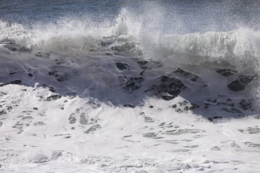 Büyük bir Atlantik dalgası Tazacorte sahiline çarpıyor. Beyaz köpük ve spreyle kırılan turkuaz suyun yakın çekimi denizin evcilleştirilmemiş gücünü gösteriyor. La Palma, Kanarya Adaları, İspanya