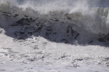 Büyük bir Atlantik dalgası Tazacorte sahiline çarpıyor. Beyaz köpük ve spreyle kırılan turkuaz suyun yakın çekimi denizin evcilleştirilmemiş gücünü gösteriyor. La Palma, Kanarya Adaları, İspanya