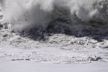 Büyük bir Atlantik dalgası Tazacorte sahiline çarpıyor. Beyaz köpük ve spreyle kırılan turkuaz suyun yakın çekimi denizin evcilleştirilmemiş gücünü gösteriyor. La Palma, Kanarya Adaları, İspanya