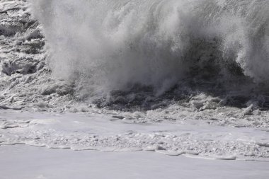 Büyük bir Atlantik dalgası Tazacorte sahiline çarpıyor. Beyaz köpük ve spreyle kırılan turkuaz suyun yakın çekimi denizin evcilleştirilmemiş gücünü gösteriyor. La Palma, Kanarya Adaları, İspanya
