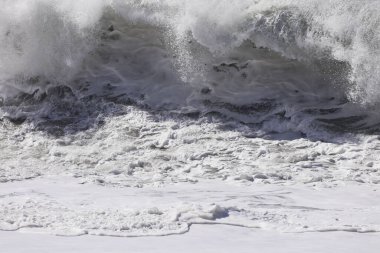 Büyük bir Atlantik dalgası Tazacorte sahiline çarpıyor. Beyaz köpük ve spreyle kırılan turkuaz suyun yakın çekimi denizin evcilleştirilmemiş gücünü gösteriyor. La Palma, Kanarya Adaları, İspanya