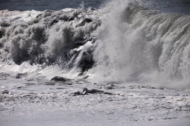 Büyük bir Atlantik dalgası Tazacorte sahiline çarpıyor. Beyaz köpük ve spreyle kırılan turkuaz suyun yakın çekimi denizin evcilleştirilmemiş gücünü gösteriyor. La Palma, Kanarya Adaları, İspanya