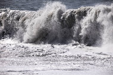 Büyük bir Atlantik dalgası Tazacorte sahiline çarpıyor. Beyaz köpük ve spreyle kırılan turkuaz suyun yakın çekimi denizin evcilleştirilmemiş gücünü gösteriyor. La Palma, Kanarya Adaları, İspanya