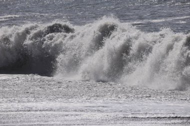 Büyük bir Atlantik dalgası Tazacorte sahiline çarpıyor. Beyaz köpük ve spreyle kırılan turkuaz suyun yakın çekimi denizin evcilleştirilmemiş gücünü gösteriyor. La Palma, Kanarya Adaları, İspanya
