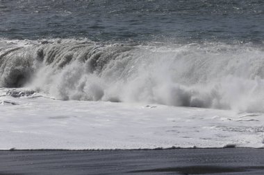 Büyük bir Atlantik dalgası Tazacorte sahiline çarpıyor. Beyaz köpük ve spreyle kırılan turkuaz suyun yakın çekimi denizin evcilleştirilmemiş gücünü gösteriyor. La Palma, Kanarya Adaları, İspanya