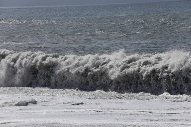 Büyük bir Atlantik dalgası Tazacorte sahiline çarpıyor. Beyaz köpük ve spreyle kırılan turkuaz suyun yakın çekimi denizin evcilleştirilmemiş gücünü gösteriyor. La Palma, Kanarya Adaları, İspanya