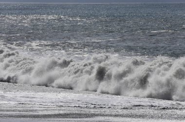 Büyük bir Atlantik dalgası Tazacorte sahiline çarpıyor. Beyaz köpük ve spreyle kırılan turkuaz suyun yakın çekimi denizin evcilleştirilmemiş gücünü gösteriyor. La Palma, Kanarya Adaları, İspanya