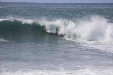 Büyük bir Atlantik dalgası Tazacorte sahiline çarpıyor. Beyaz köpük ve spreyle kırılan turkuaz suyun yakın çekimi denizin evcilleştirilmemiş gücünü gösteriyor. La Palma, Kanarya Adaları, İspanya