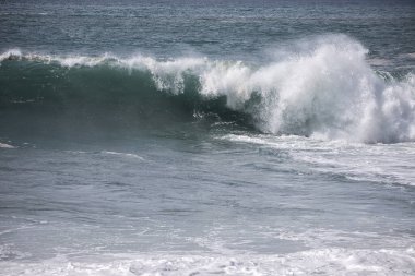 Büyük bir Atlantik dalgası Tazacorte sahiline çarpıyor. Beyaz köpük ve spreyle kırılan turkuaz suyun yakın çekimi denizin evcilleştirilmemiş gücünü gösteriyor. La Palma, Kanarya Adaları, İspanya