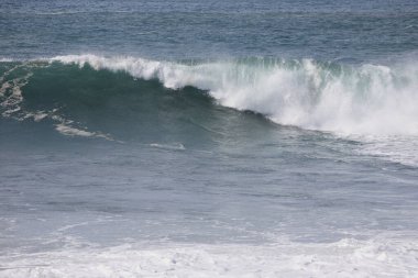 Büyük bir Atlantik dalgası Tazacorte sahiline çarpıyor. Beyaz köpük ve spreyle kırılan turkuaz suyun yakın çekimi denizin evcilleştirilmemiş gücünü gösteriyor. La Palma, Kanarya Adaları, İspanya