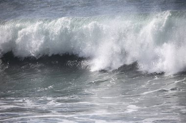 Büyük bir Atlantik dalgası Tazacorte sahiline çarpıyor. Beyaz köpük ve spreyle kırılan turkuaz suyun yakın çekimi denizin evcilleştirilmemiş gücünü gösteriyor. La Palma, Kanarya Adaları, İspanya