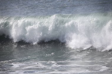 Büyük bir Atlantik dalgası Tazacorte sahiline çarpıyor. Beyaz köpük ve spreyle kırılan turkuaz suyun yakın çekimi denizin evcilleştirilmemiş gücünü gösteriyor. La Palma, Kanarya Adaları, İspanya