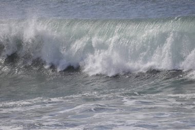 Büyük bir Atlantik dalgası Tazacorte sahiline çarpıyor. Beyaz köpük ve spreyle kırılan turkuaz suyun yakın çekimi denizin evcilleştirilmemiş gücünü gösteriyor. La Palma, Kanarya Adaları, İspanya