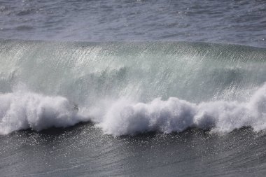 Büyük bir Atlantik dalgası Tazacorte sahiline çarpıyor. Beyaz köpük ve spreyle kırılan turkuaz suyun yakın çekimi denizin evcilleştirilmemiş gücünü gösteriyor. La Palma, Kanarya Adaları, İspanya