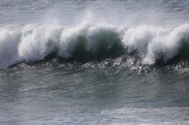 Büyük bir Atlantik dalgası Tazacorte sahiline çarpıyor. Beyaz köpük ve spreyle kırılan turkuaz suyun yakın çekimi denizin evcilleştirilmemiş gücünü gösteriyor. La Palma, Kanarya Adaları, İspanya