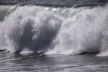 Büyük bir Atlantik dalgası Tazacorte sahiline çarpıyor. Beyaz köpük ve spreyle kırılan turkuaz suyun yakın çekimi denizin evcilleştirilmemiş gücünü gösteriyor. La Palma, Kanarya Adaları, İspanya