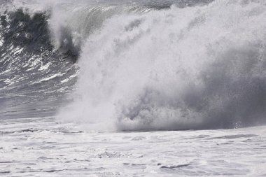 Büyük bir Atlantik dalgası Tazacorte sahiline çarpıyor. Beyaz köpük ve spreyle kırılan turkuaz suyun yakın çekimi denizin evcilleştirilmemiş gücünü gösteriyor. La Palma, Kanarya Adaları, İspanya