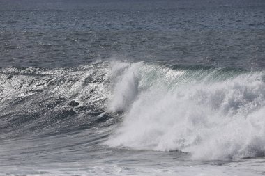 Büyük bir Atlantik dalgası Tazacorte sahiline çarpıyor. Beyaz köpük ve spreyle kırılan turkuaz suyun yakın çekimi denizin evcilleştirilmemiş gücünü gösteriyor. La Palma, Kanarya Adaları, İspanya