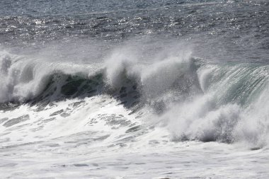 Büyük bir Atlantik dalgası Tazacorte sahiline çarpıyor. Beyaz köpük ve spreyle kırılan turkuaz suyun yakın çekimi denizin evcilleştirilmemiş gücünü gösteriyor. La Palma, Kanarya Adaları, İspanya