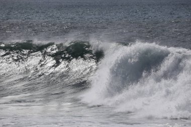 Büyük bir Atlantik dalgası Tazacorte sahiline çarpıyor. Beyaz köpük ve spreyle kırılan turkuaz suyun yakın çekimi denizin evcilleştirilmemiş gücünü gösteriyor. La Palma, Kanarya Adaları, İspanya