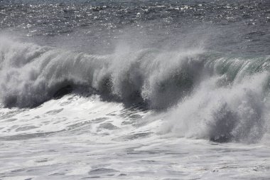 Büyük bir Atlantik dalgası Tazacorte sahiline çarpıyor. Beyaz köpük ve spreyle kırılan turkuaz suyun yakın çekimi denizin evcilleştirilmemiş gücünü gösteriyor. La Palma, Kanarya Adaları, İspanya