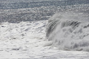 Büyük bir Atlantik dalgası Tazacorte sahiline çarpıyor. Beyaz köpük ve spreyle kırılan turkuaz suyun yakın çekimi denizin evcilleştirilmemiş gücünü gösteriyor. La Palma, Kanarya Adaları, İspanya