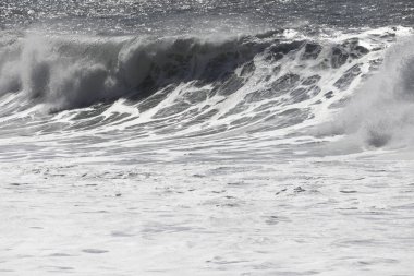 Büyük bir Atlantik dalgası Tazacorte sahiline çarpıyor. Beyaz köpük ve spreyle kırılan turkuaz suyun yakın çekimi denizin evcilleştirilmemiş gücünü gösteriyor. La Palma, Kanarya Adaları, İspanya