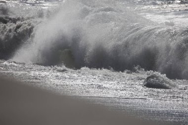 Tazacorte 'deki siyah kumlu sahilin dramatik geniş açılı görüntüsü. Turkuaz dalgalar kırılıyor. La Palma 'nın volkanik kıyı şeridi kasvetli, bulutlu gökyüzünün altında dalgalı su blokları var.